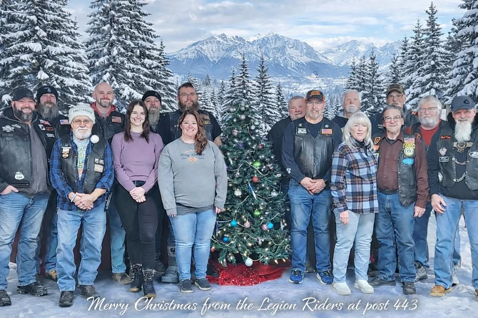 Sanford American Legion Riders Chapter #443 group photo in front of a Christmas tree with snowy mountains in the background
